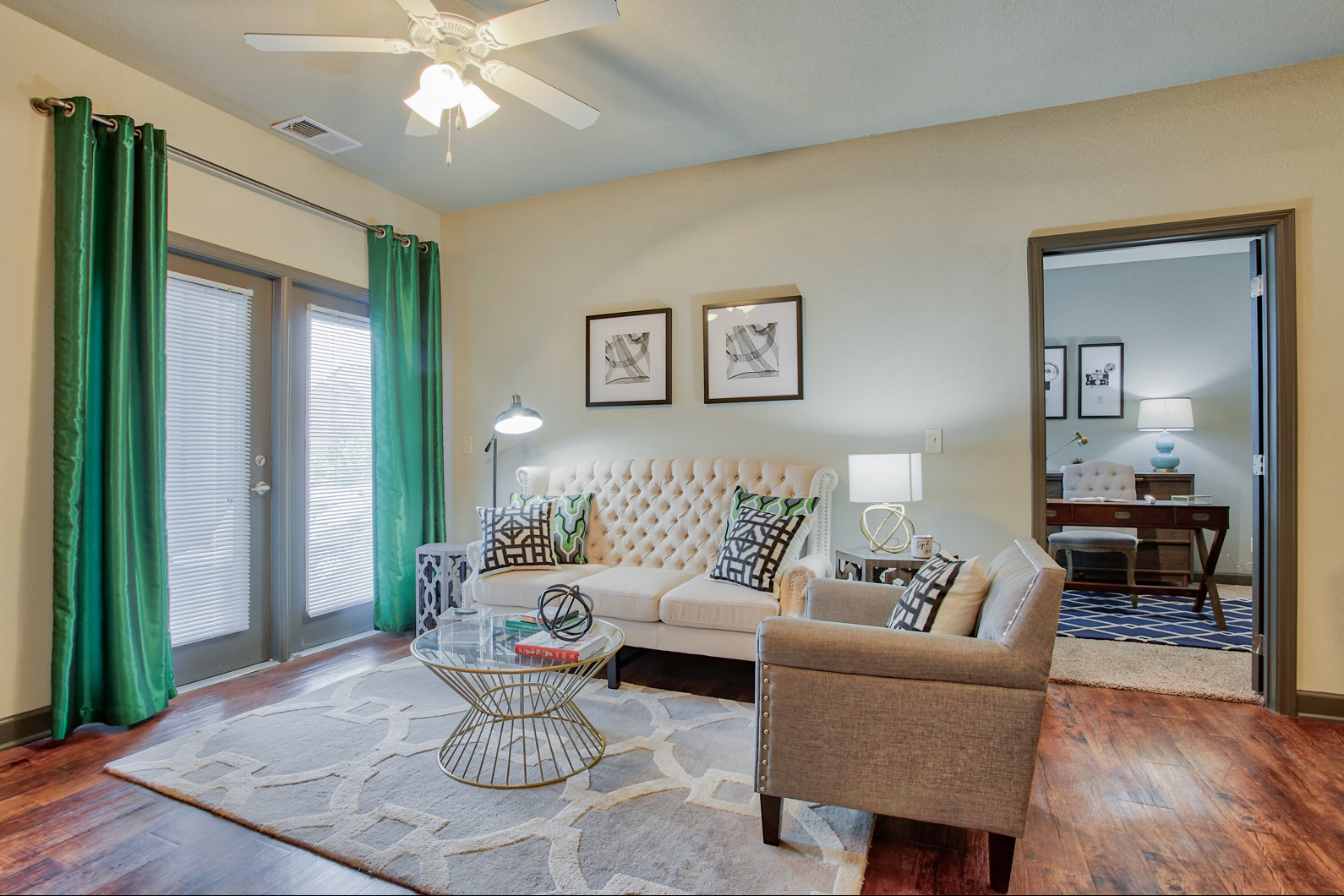 a living room with a couch and a chair and a ceiling fan