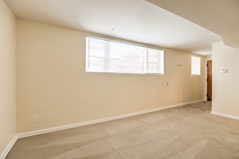A room with a carpeted floor and a window with blinds.