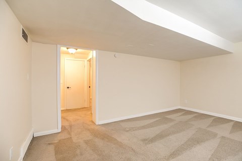 A room with a carpeted floor and a doorway leading to another room.
