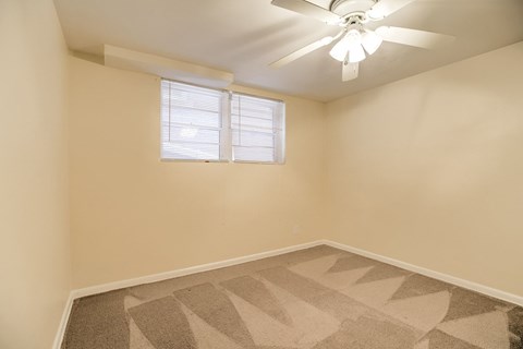 A room with a ceiling fan and a window with blinds.