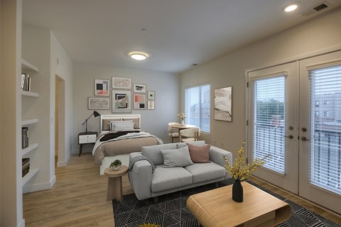 A well-lit bedroom with a large bed and a grey couch.