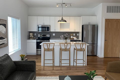 A kitchen with a black sofa and a bar stool.