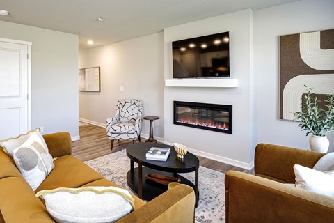 A living room with a fireplace and a television mounted above it.