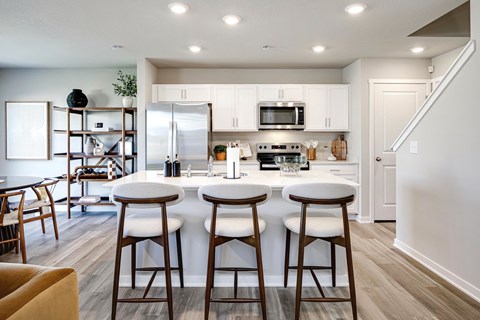 A kitchen with a bar stool in front of a counter.