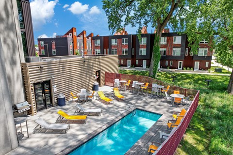 A pool surrounded by chairs and tables in a sunny backyard.
