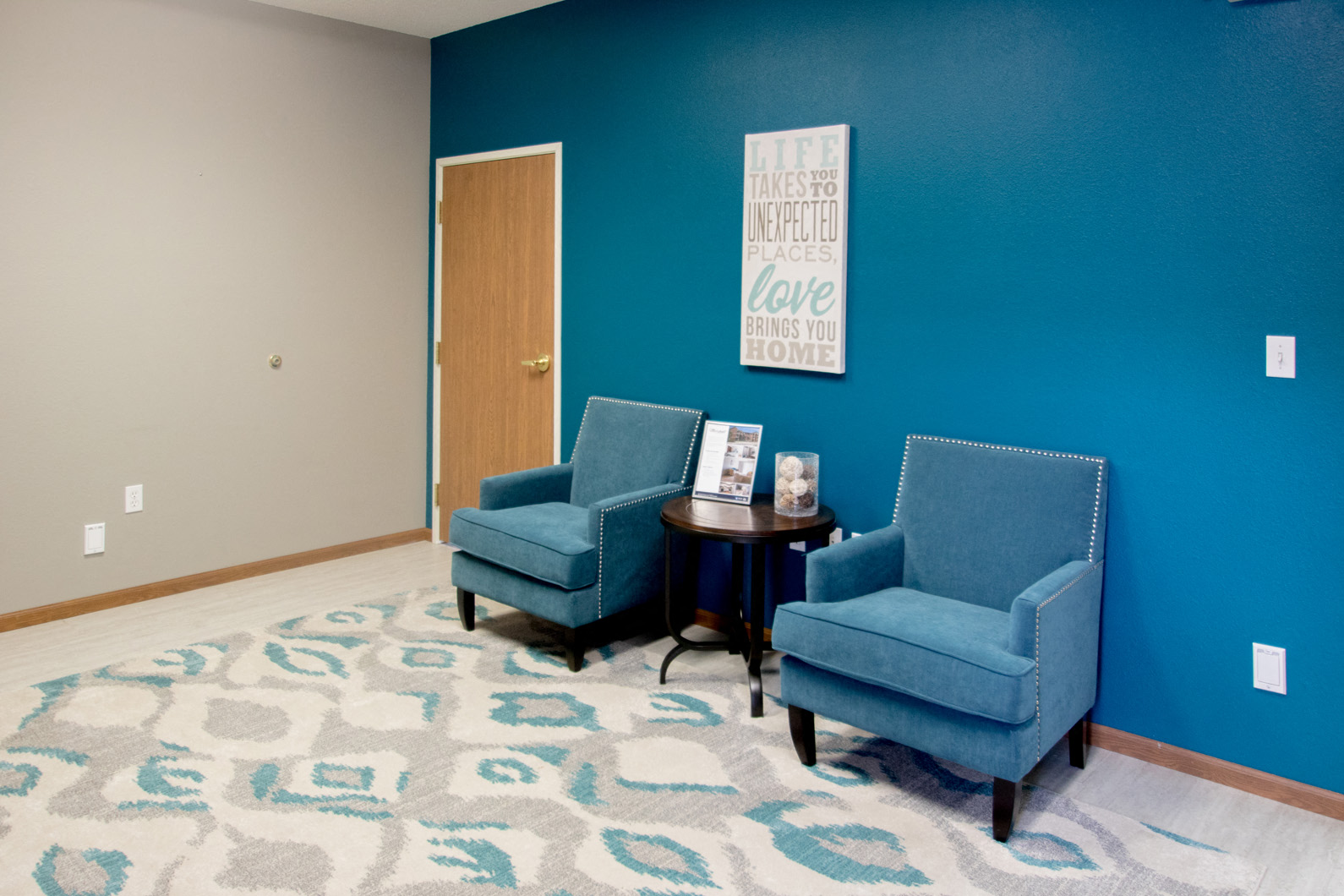 two blue chairs in a room with a blue wall and a table