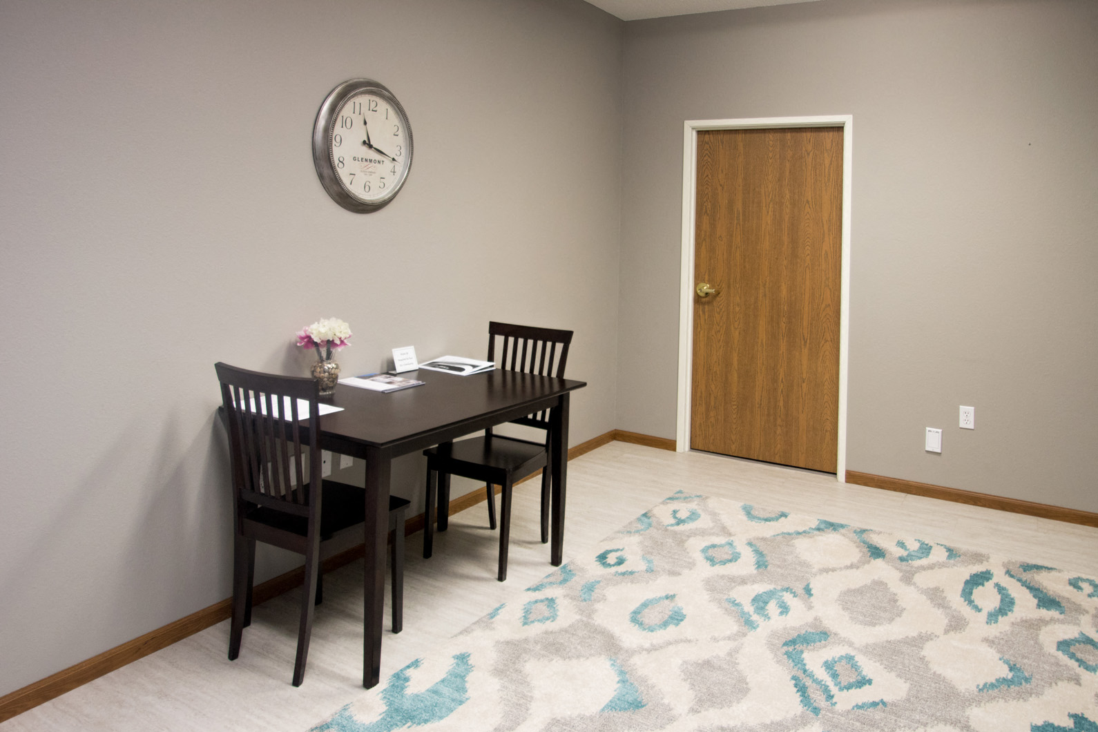 a dining room with a table and chairs and a clock on the wall