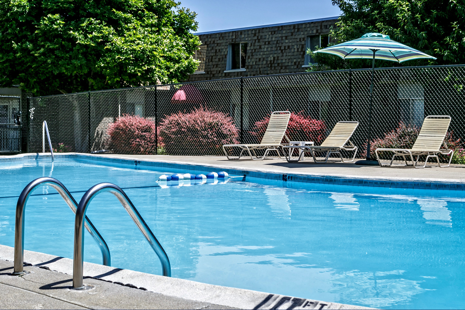 a swimming pool with chairs and an umbrella next to it