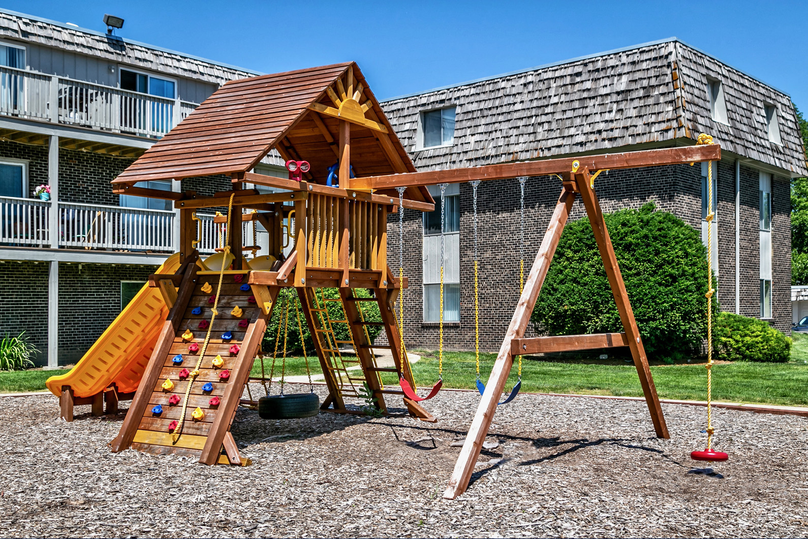 a wooden swing set in a playground in front of a building