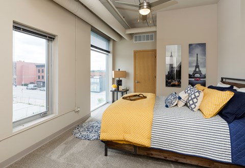 A bedroom with a bed, pillows, and pictures on the wall.