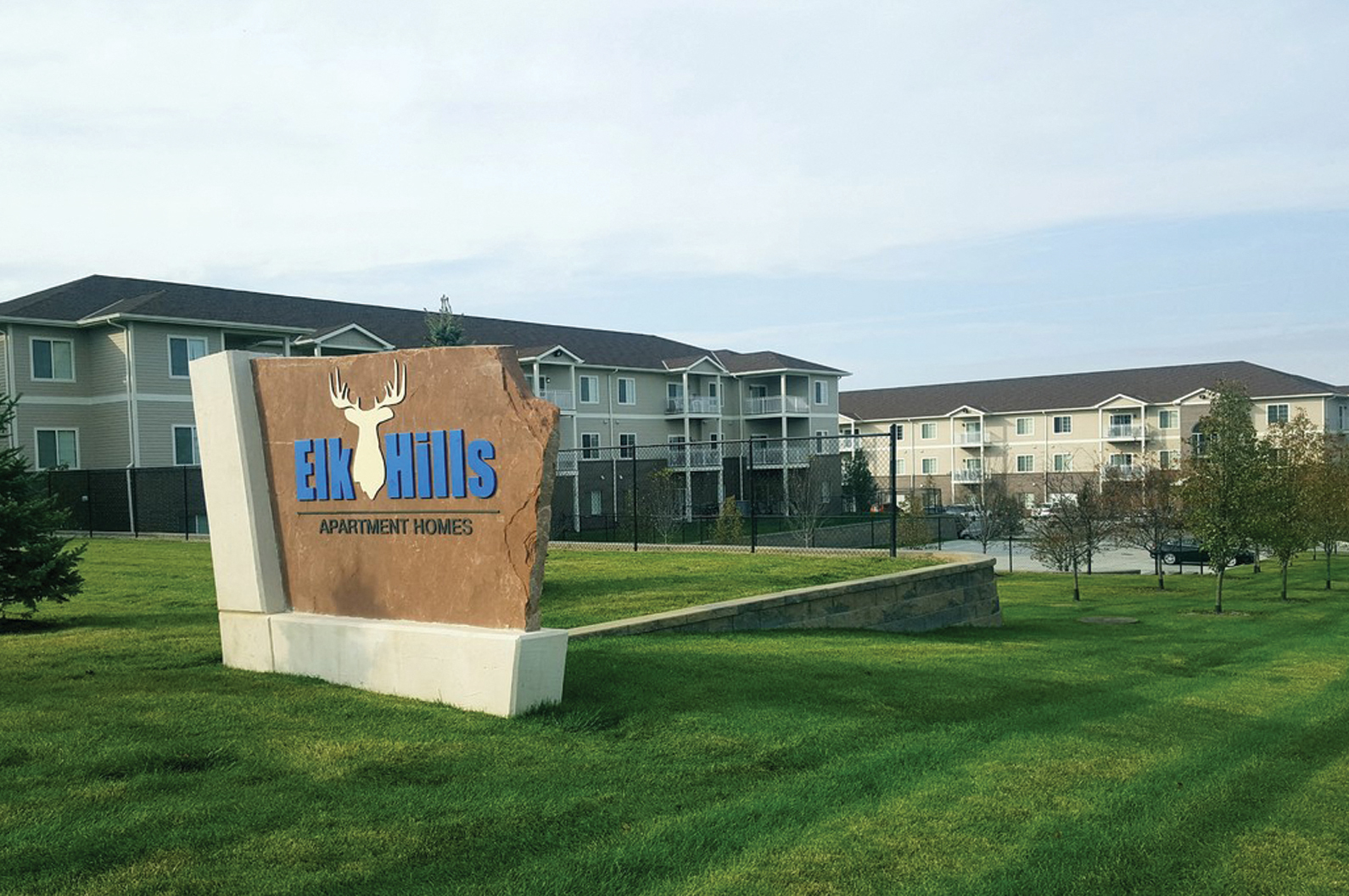 a sign for the elkhorns apartment complex with apartments in the background