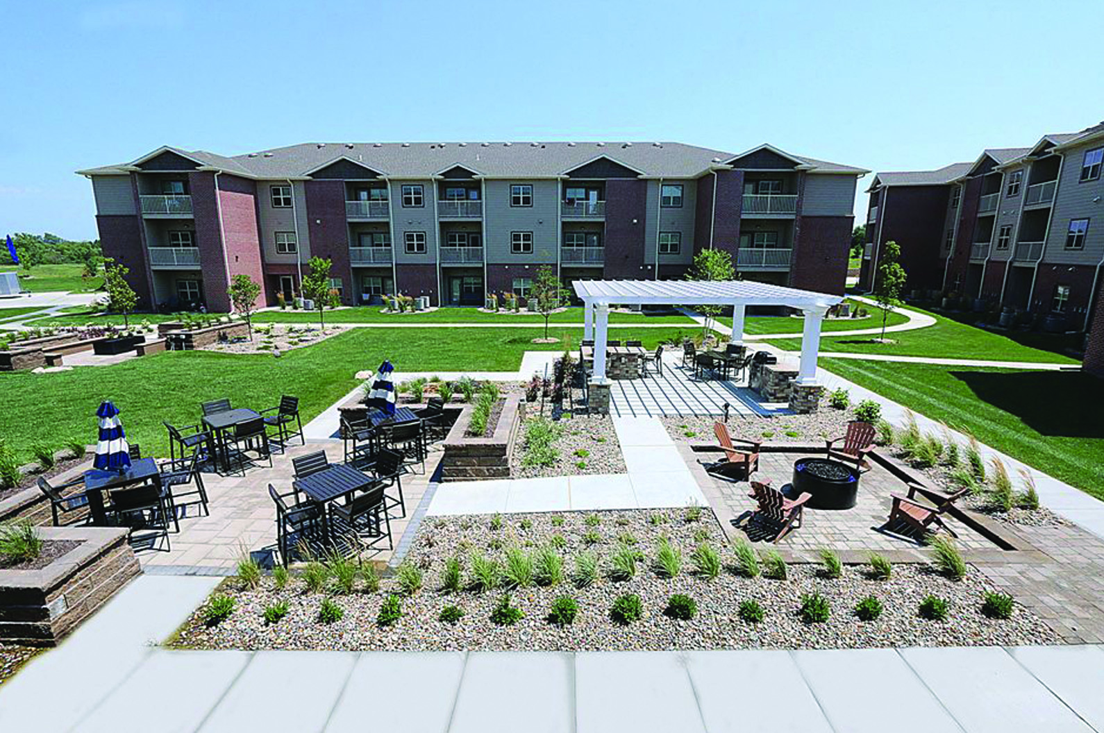 an outdoor area with a pavilion and tables in front of an apartment building