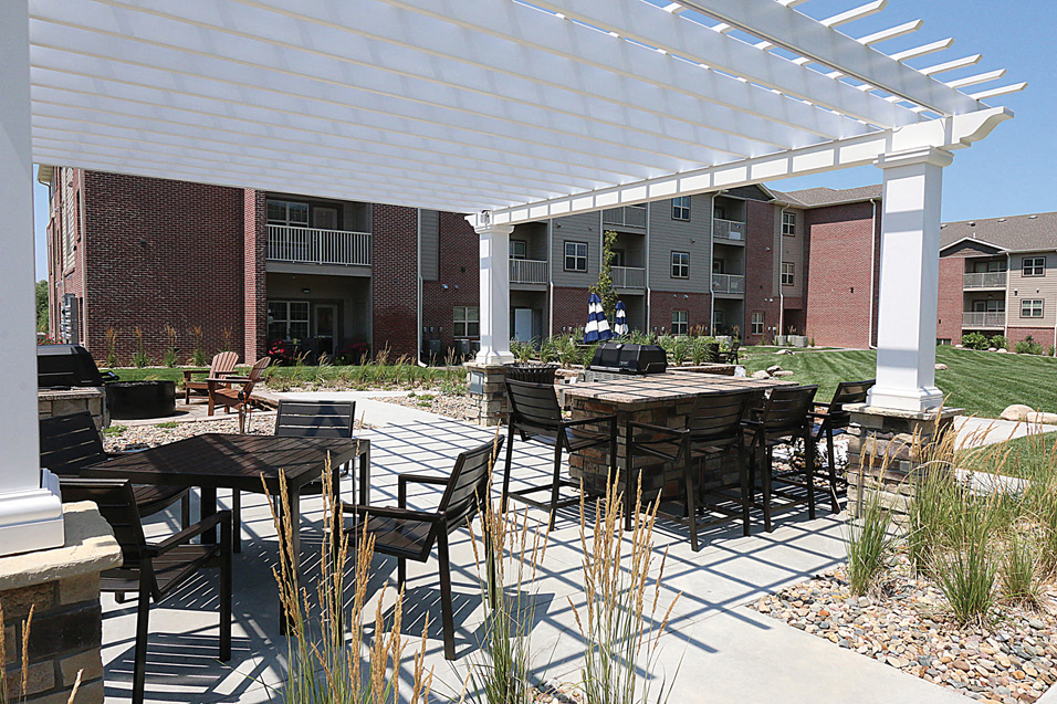 an outdoor patio with tables and chairs under a white canopy