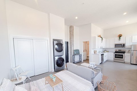 A modern living room with a grey sofa and a kitchen in the background.