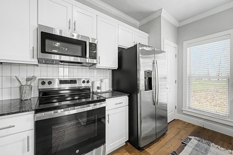 A black refrigerator is in a white kitchen.