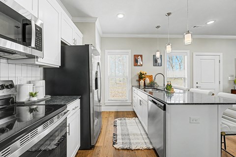 A modern kitchen with black and white appliances and a black countertop.