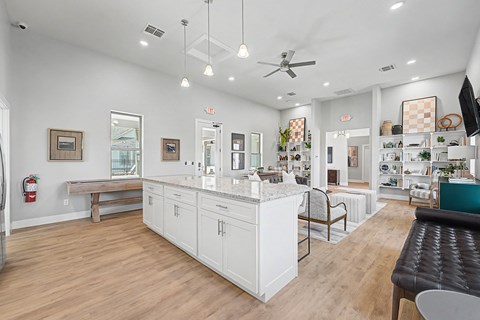 A well-lit, spacious kitchen and dining area with white cabinetry and a wooden floor.