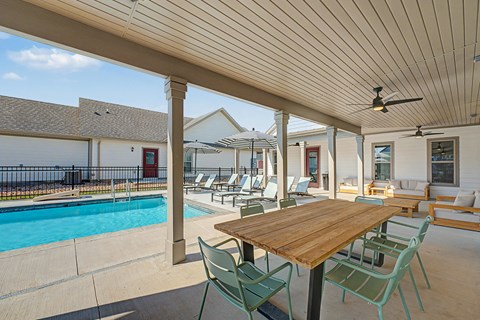 A wooden table is surrounded by chairs on a patio.