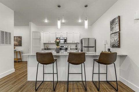 A kitchen with white cabinets and a white island with brown barstools.