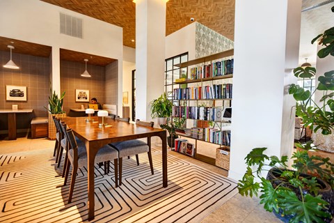 A long wooden table with chairs and a bookshelf in the background.