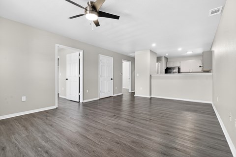 A spacious room with a ceiling fan and wooden flooring.