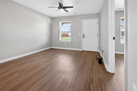 A room with a ceiling fan and wooden flooring.