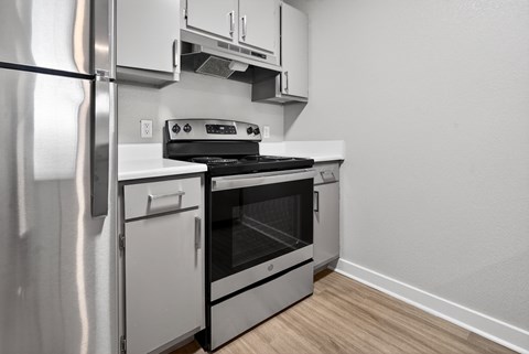 A modern kitchen with a stainless steel refrigerator and an oven with a stove on top.