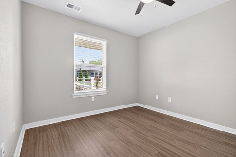 A room with a window showing a view of a building and trees outside.