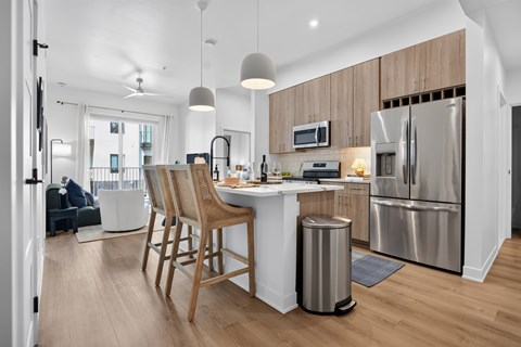 A modern kitchen with wooden chairs and stainless steel appliances.