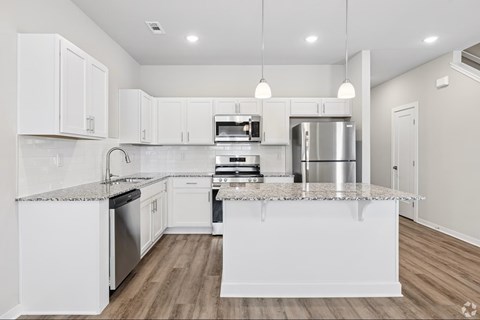 A modern kitchen with white cabinets and stainless steel appliances.