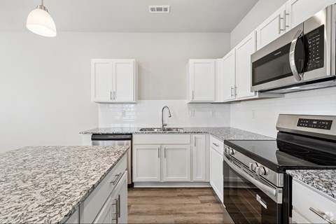 A kitchen with white cabinets and a granite countertop.