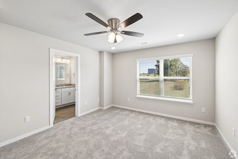 A spacious room with a ceiling fan and carpeted floor.