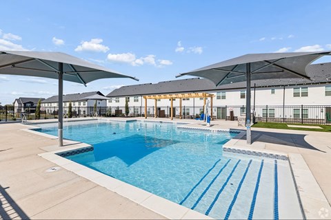 A large outdoor swimming pool with a slide and sun shades.