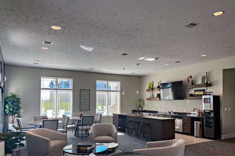a lobby with chairs and tables and a kitchen with a counter