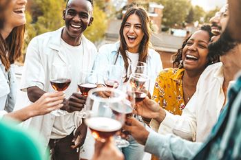 a group of people laughing and holding wine glasses