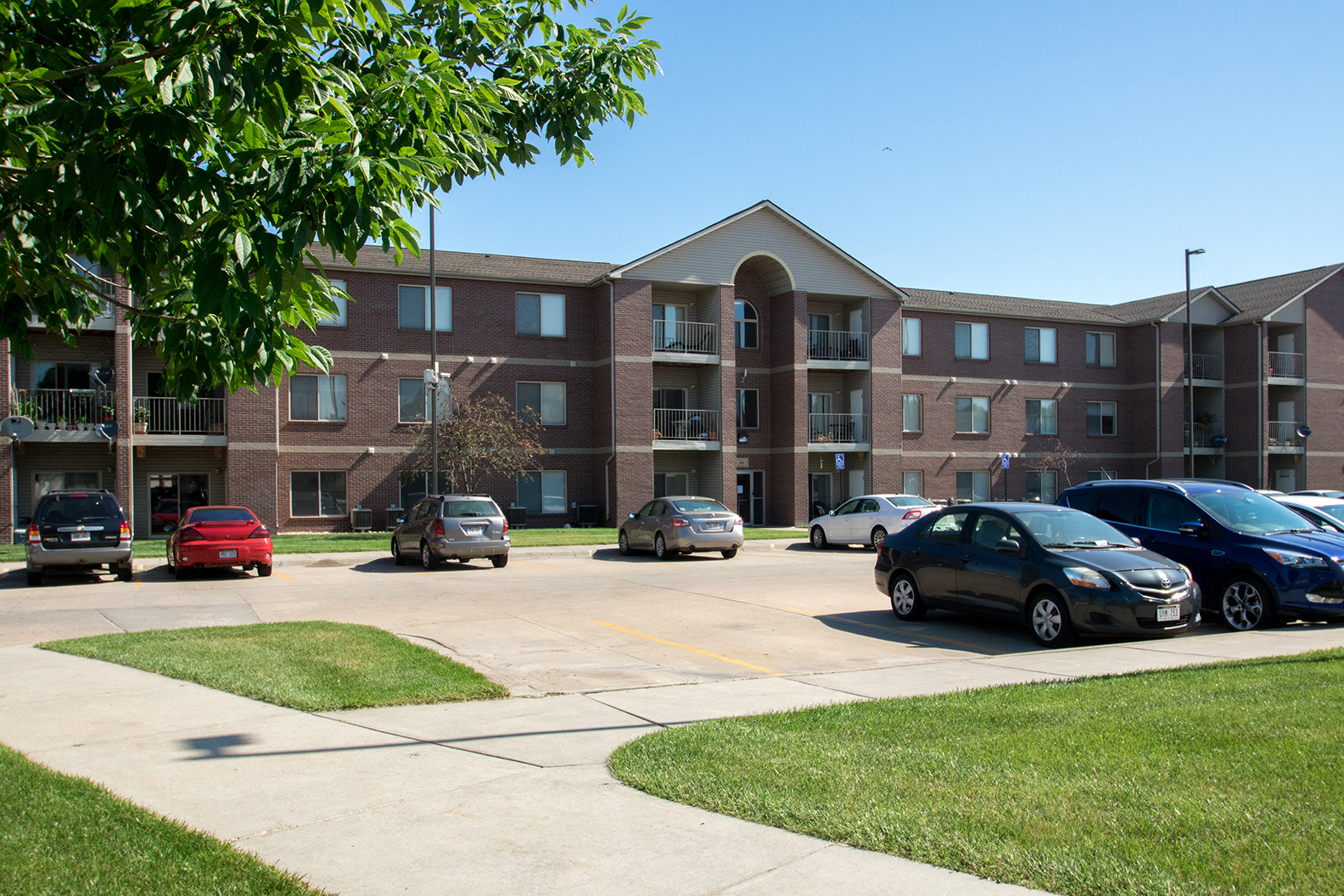 an apartment building with cars parked in a parking lot