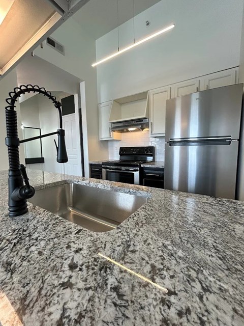A kitchen with a granite countertop and stainless steel appliances.