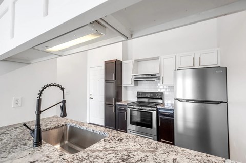 A kitchen with a sink, stove, and refrigerator.