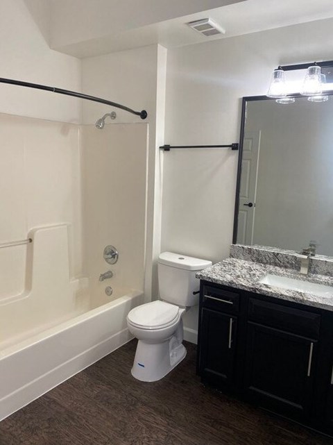 A white toilet sits in a bathroom next to a bathtub.