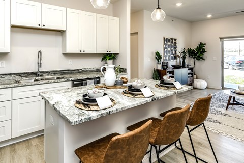 an open kitchen and dining area with a marble counter top