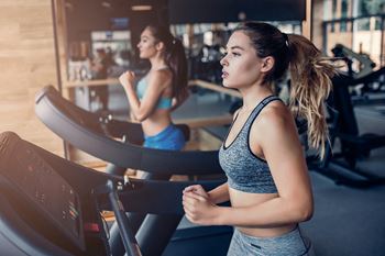 two women running on a treadmill at the gym