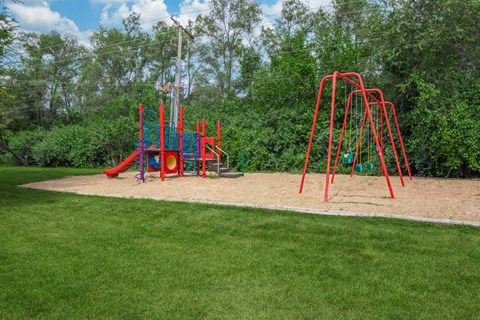A playground with a red swing set and a blue slide.