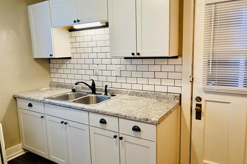 A kitchen with white cabinets and a marble countertop.