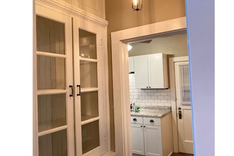 A white kitchen with a glass door cabinet.