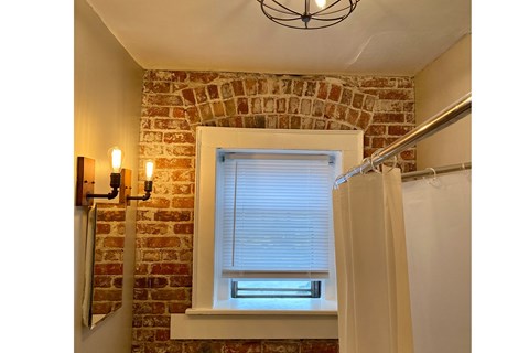 A bathroom with a brick wall and a window.