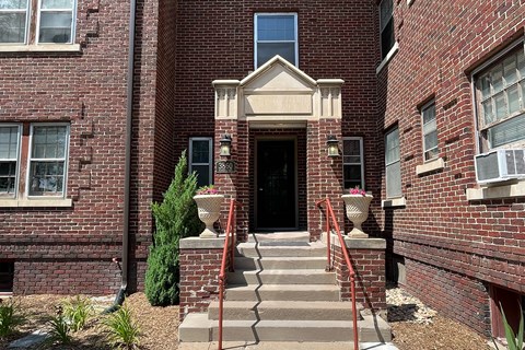 A red brick building with a black door and a small window above it.