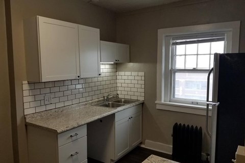 A kitchen with white cabinets and a tiled backsplash.