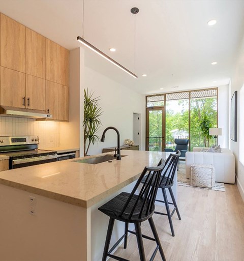 A modern kitchen with wooden cabinets and a large island with chairs.