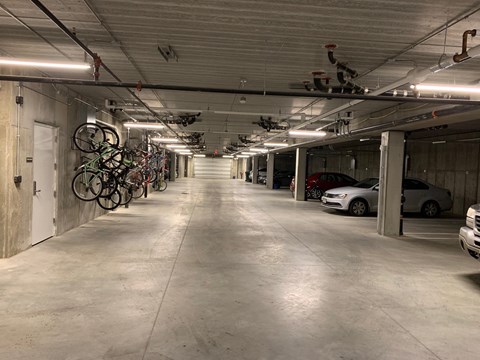A long, narrow garage with bicycles on the left and cars on the right.