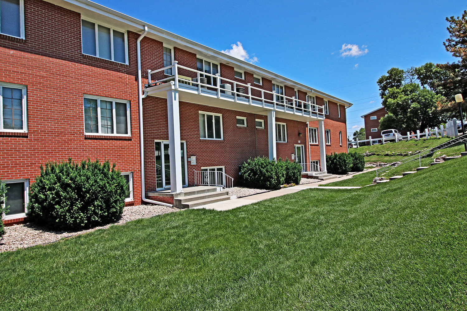 a large brick apartment building with a porch and a lawn